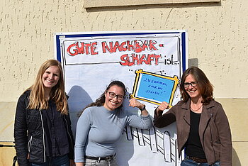 Drei Frauen vor Plakat zur Quartiersarbeit